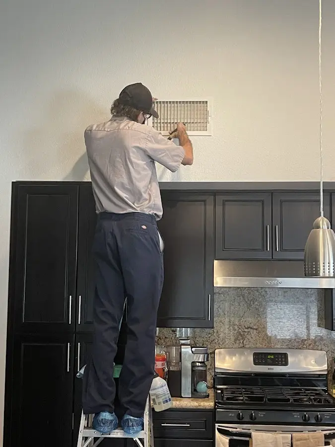 Technician inspecting an air vent during HVAC service in Shelby